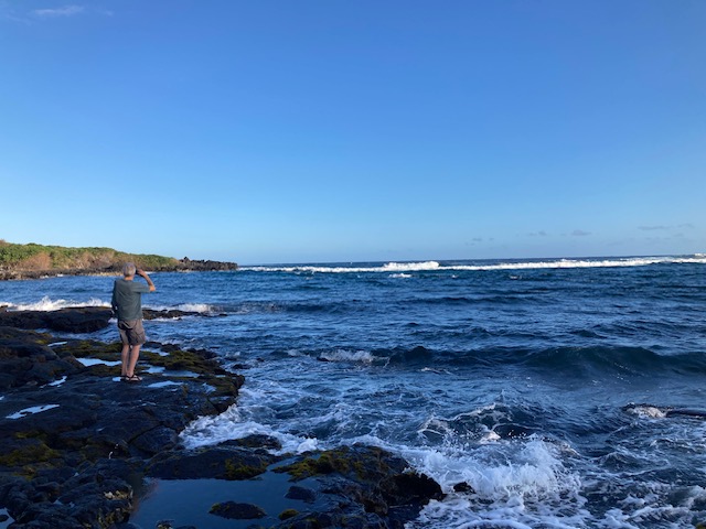 man standing on rocks looking out over water