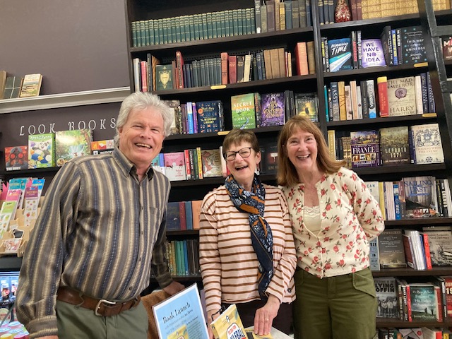 2 women and a man standing in bookstore holding book To Die for Pickleball