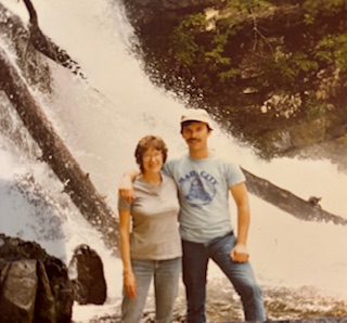 male and female standing in front of waterfall
